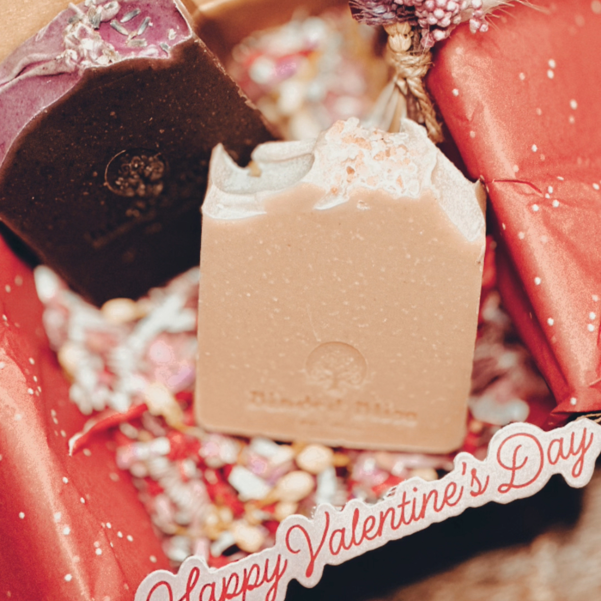 wo handcrafted soaps in red Valentine's Day packaging with natural accents and a festive design.