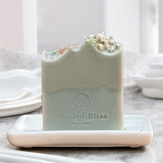 Freya handmade aloe vera soap by Blnded Bliss with soft ocean-inspired colors and floral top, displayed on a white ceramic soap dish.