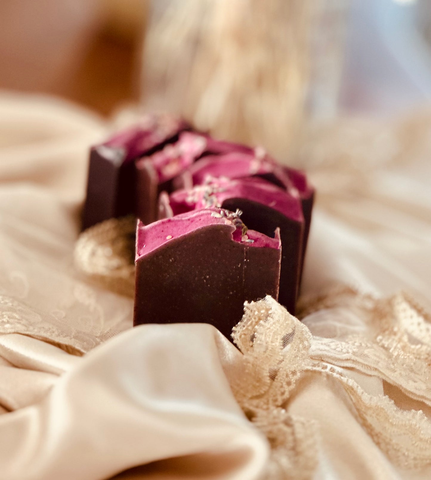 A side-angle shot of lavender soap bars showcasing their deep, dark base and vibrant purple top, with dried lavender buds adding a natural touch.