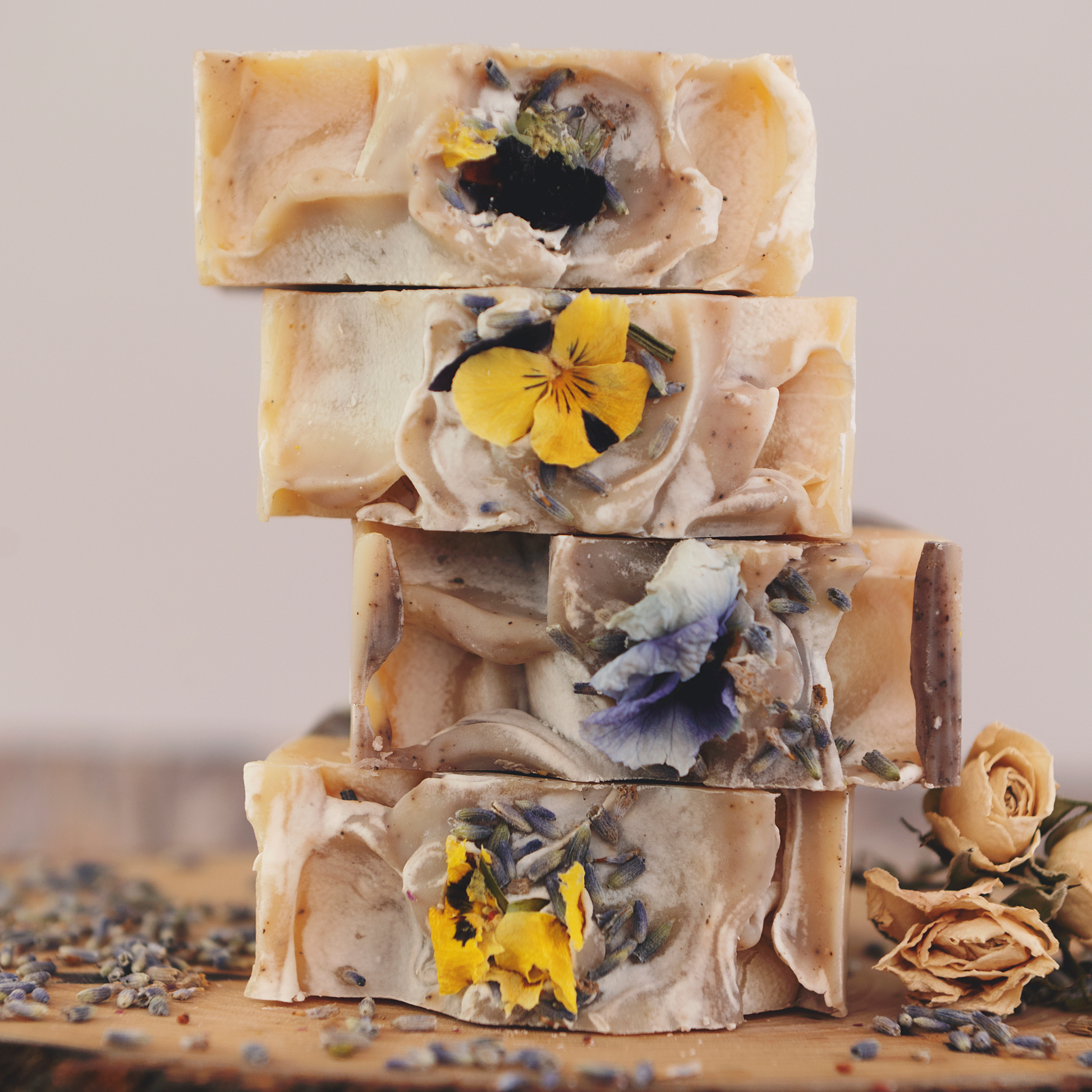 Four bars of Blnded Bliss natural Lavender and Frankincense soap stacked on a log.