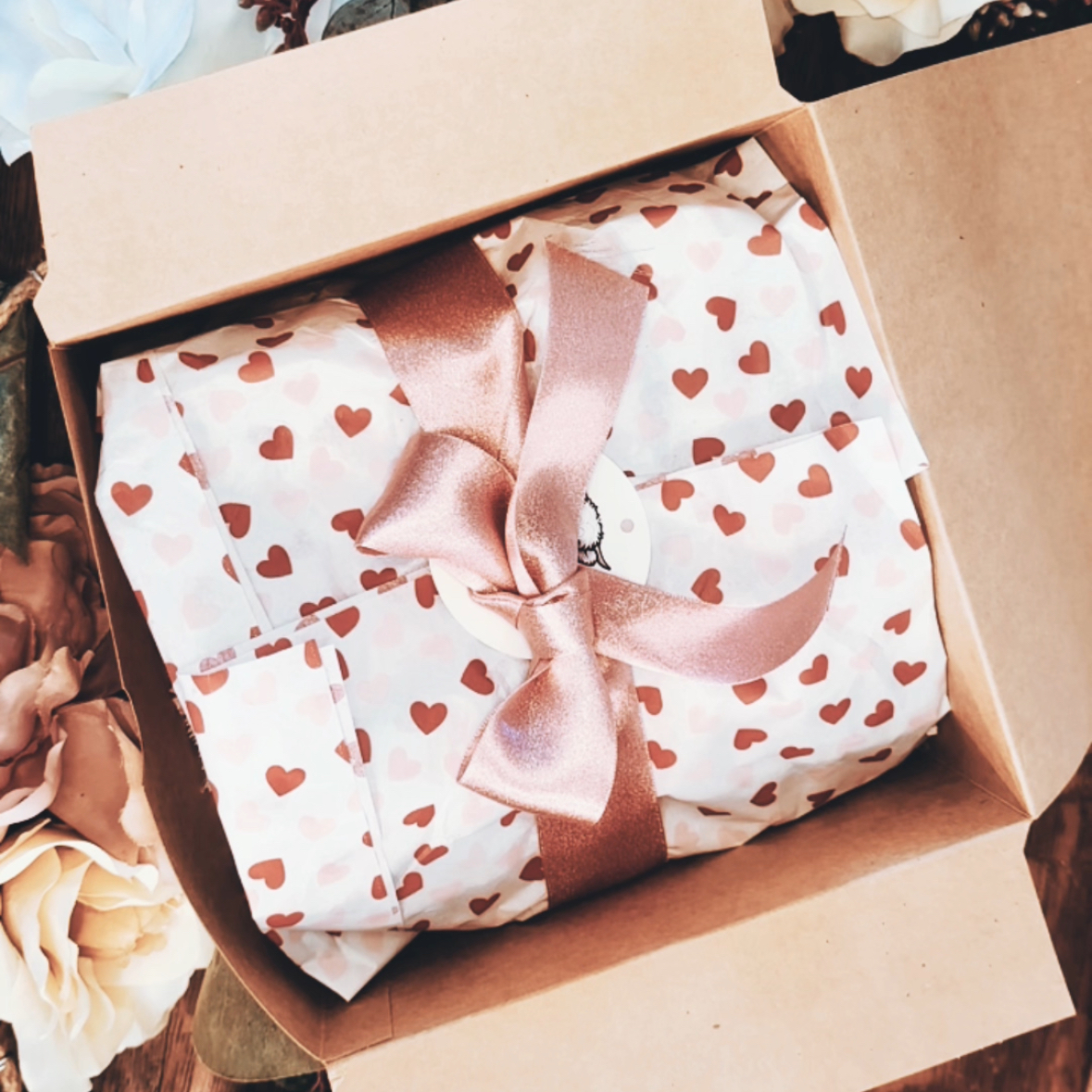 Beautifully wrapped Valentine's Day gift box with heart tissue paper and pink satin ribbon.